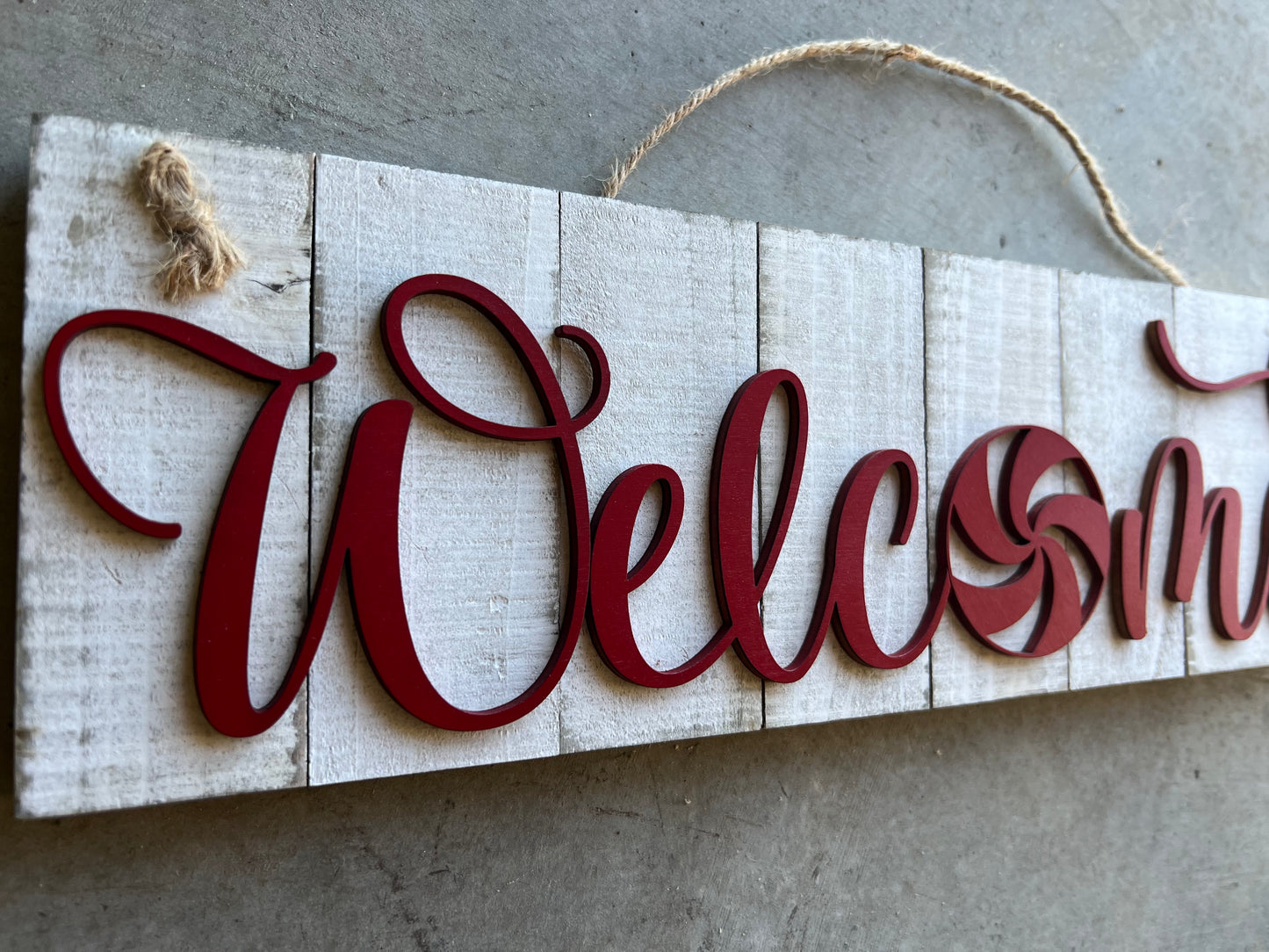 white wooden sign with WELCOME in red and the shape of a peppermint as the O