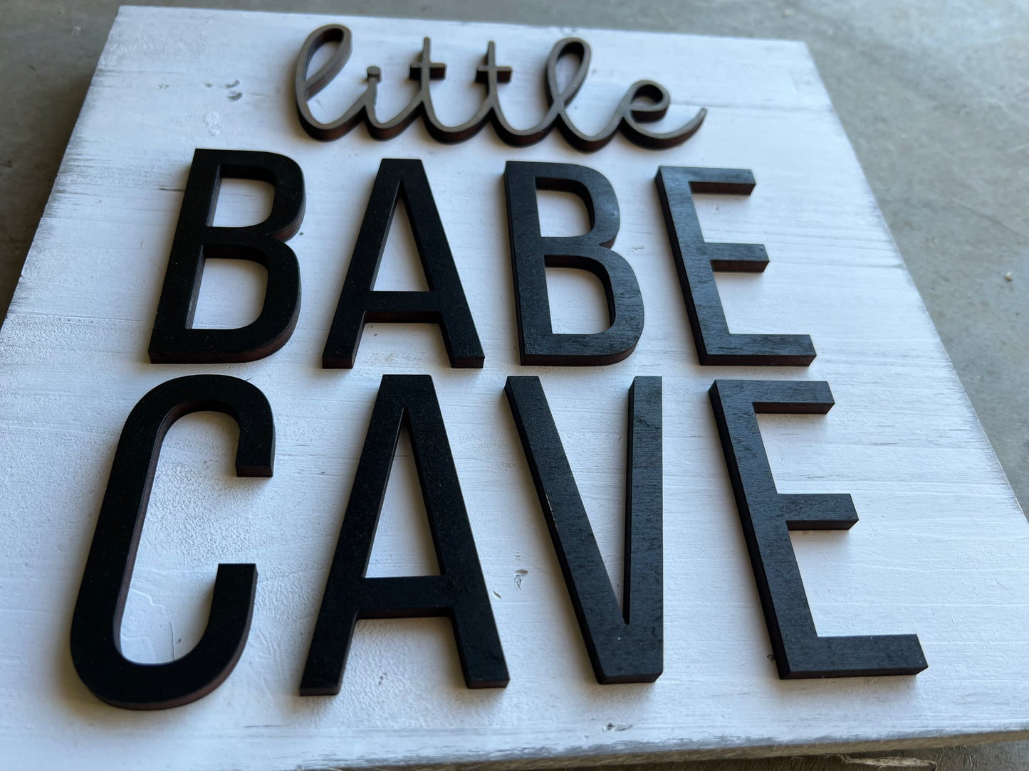 square wooden sign with the quote "little babe cave"