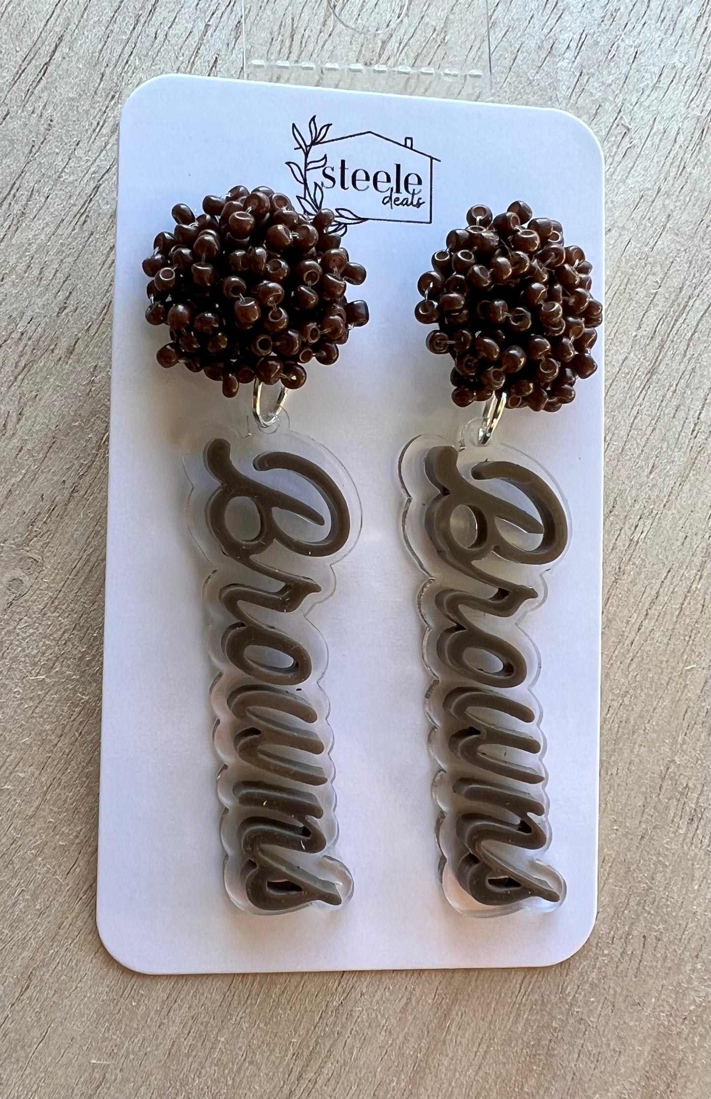 Brown beaded earrings with layered acrylic football team dangled down