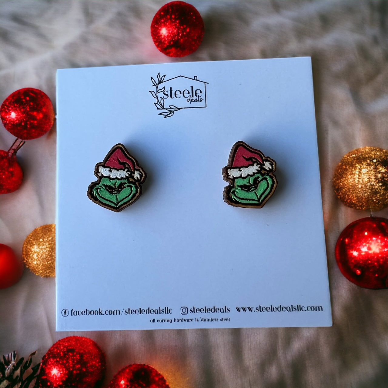 wood stud earrings in the shape of the Green Guy wearing a red Santa hat