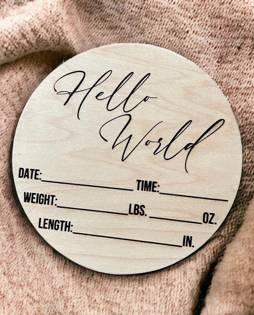 circle wooden sign saying Hello world and spots for birth date, time, weight, lbs, and length