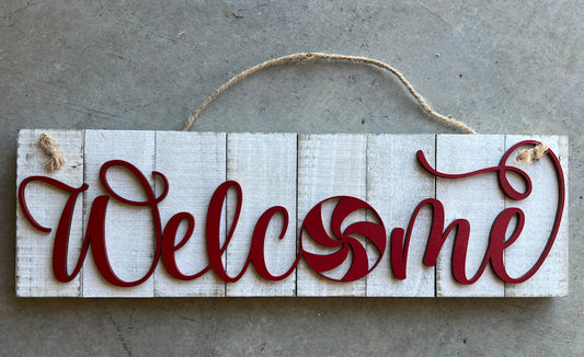 white wooden sign with WELCOME in red and the shape of a peppermint as the O