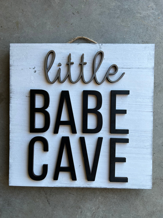 square wooden sign with the quote "little babe cave"
