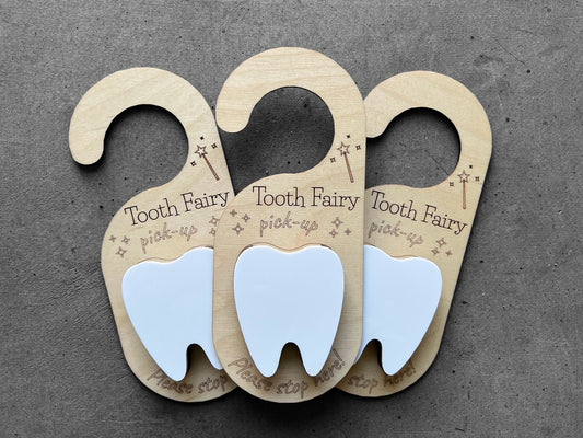wooden door hanger with the quote "tooth fairy pickup please stop here" White tooth in the center with a pocket to place the actual tooth